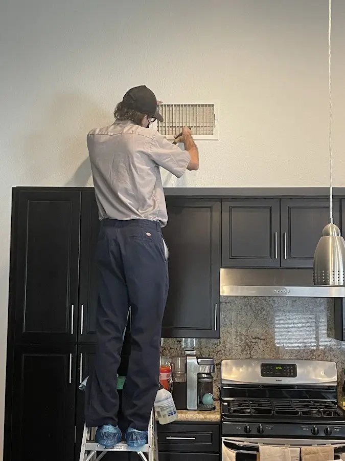 Technician inspecting an air vent during HVAC service in Roswell